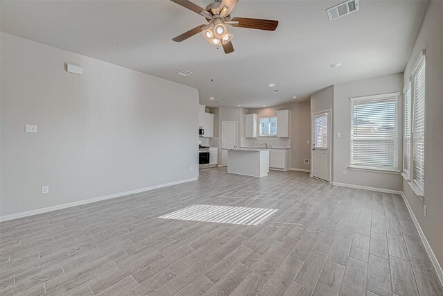 unfurnished living room featuring ceiling fan and light wood-type flooring