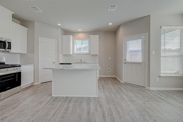 kitchen with white cabinetry, light hardwood / wood-style flooring, and stainless steel appliances