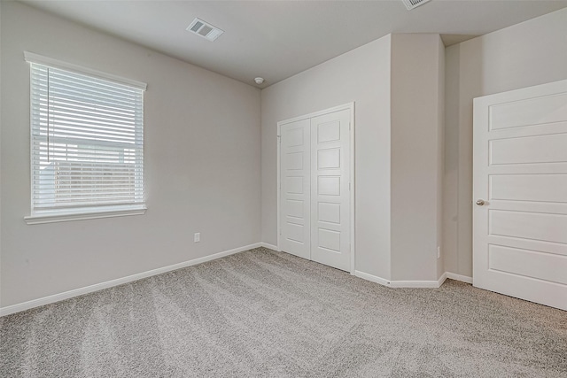 unfurnished bedroom featuring light colored carpet and a closet