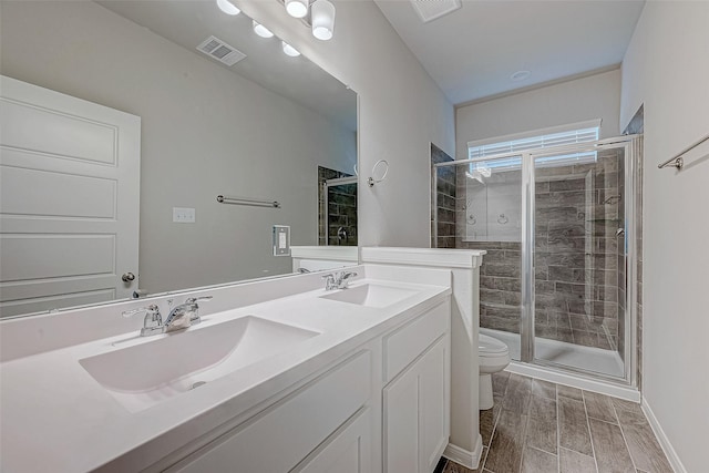 bathroom featuring a shower with door, vanity, and toilet