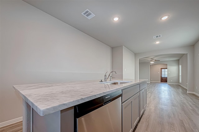 kitchen featuring light wood-type flooring, stainless steel dishwasher, a kitchen island with sink, ceiling fan, and sink