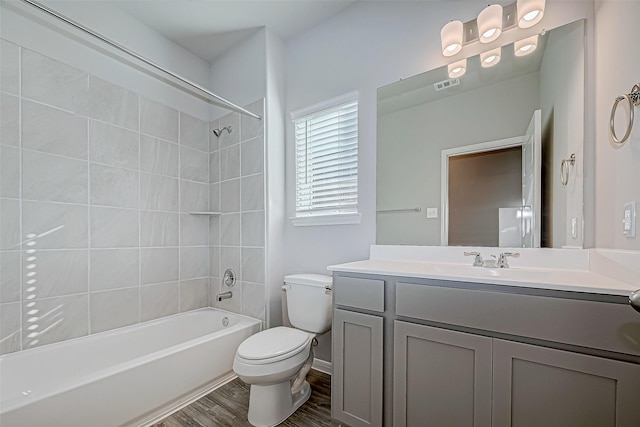 full bathroom featuring hardwood / wood-style flooring, vanity, toilet, and tiled shower / bath