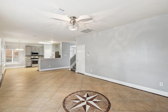 unfurnished living room with light tile patterned flooring and ceiling fan with notable chandelier