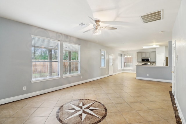 unfurnished living room with ceiling fan with notable chandelier and light tile patterned floors