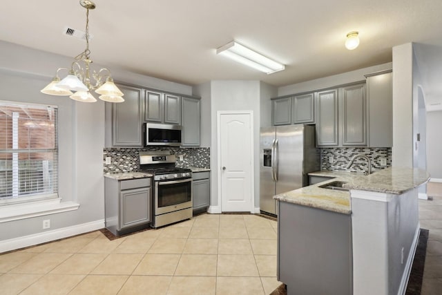 kitchen featuring decorative light fixtures, gray cabinets, appliances with stainless steel finishes, a notable chandelier, and kitchen peninsula