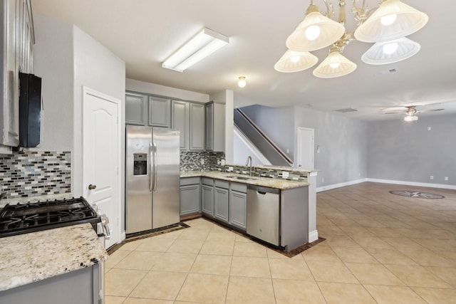 kitchen featuring appliances with stainless steel finishes, tasteful backsplash, pendant lighting, and gray cabinetry