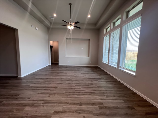 unfurnished room with ceiling fan, a towering ceiling, and dark hardwood / wood-style floors