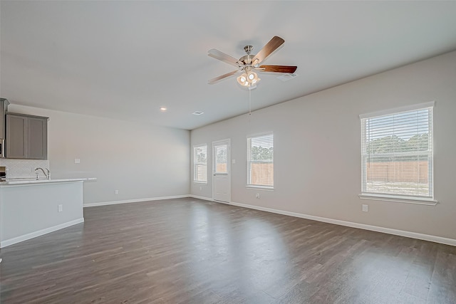 unfurnished living room featuring dark wood-type flooring, sink, and ceiling fan