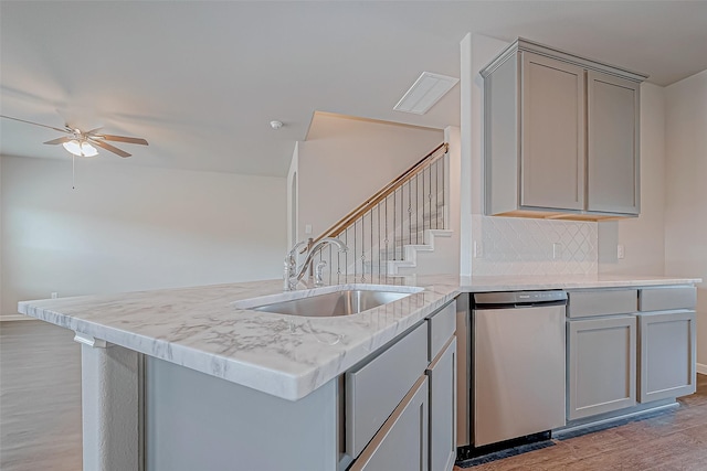 kitchen featuring sink, dishwasher, gray cabinetry, light hardwood / wood-style floors, and decorative backsplash