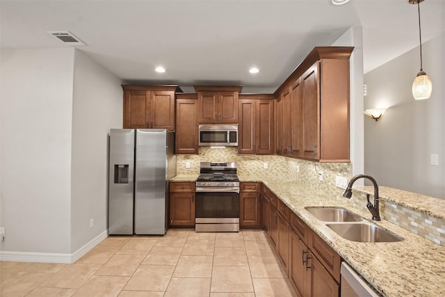 kitchen with backsplash, sink, light stone countertops, decorative light fixtures, and stainless steel appliances