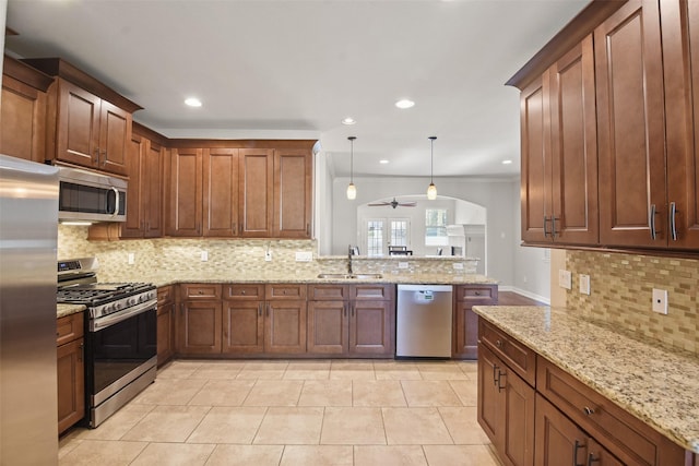 kitchen with sink, ceiling fan, light stone countertops, decorative light fixtures, and stainless steel appliances