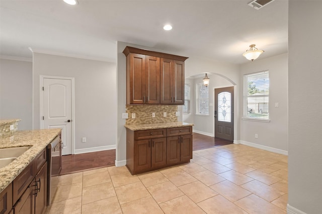 kitchen featuring dishwasher, light stone countertops, backsplash, and light tile patterned floors