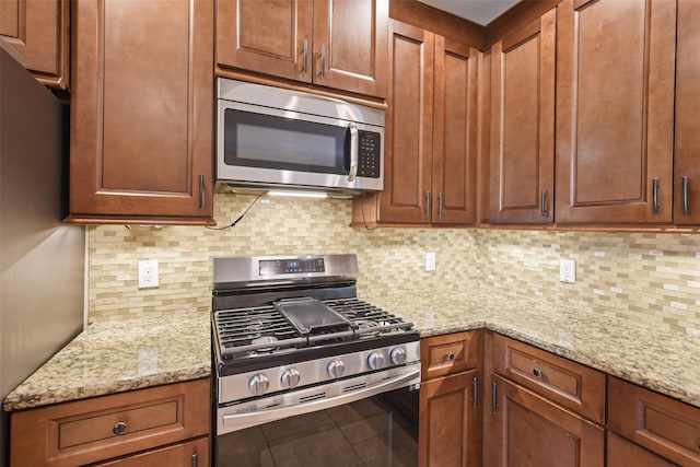 kitchen featuring backsplash, light stone counters, and appliances with stainless steel finishes