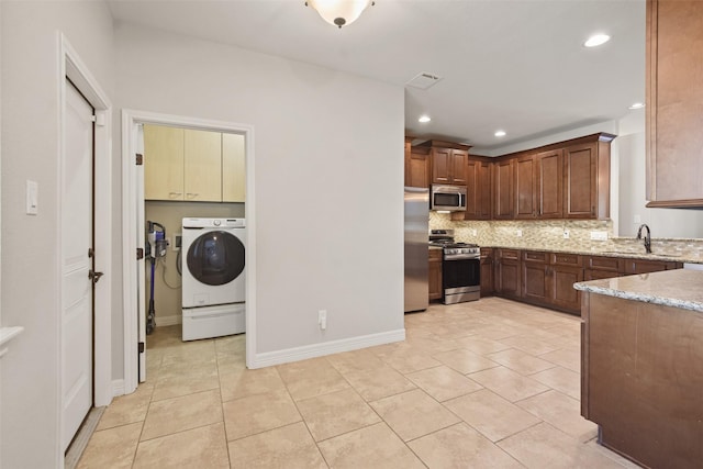 kitchen with sink, decorative backsplash, light tile patterned floors, light stone counters, and stainless steel appliances