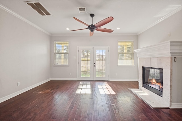 unfurnished living room featuring french doors, ceiling fan, ornamental molding, and a tiled fireplace