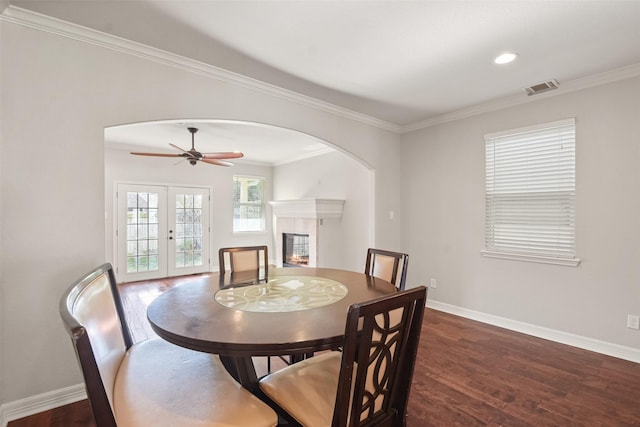 dining room with ceiling fan, dark hardwood / wood-style floors, ornamental molding, and french doors