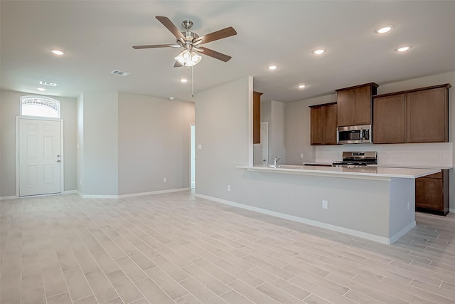 kitchen featuring kitchen peninsula, ceiling fan, light hardwood / wood-style flooring, and stainless steel appliances