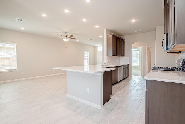 kitchen with appliances with stainless steel finishes, light wood-type flooring, dark brown cabinetry, ceiling fan, and sink