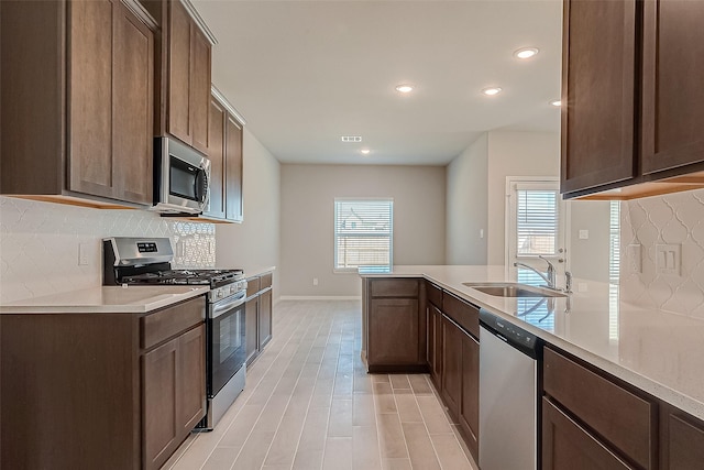 kitchen with backsplash, sink, dark brown cabinetry, and stainless steel appliances