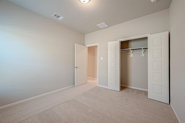 unfurnished bedroom with light colored carpet and a closet