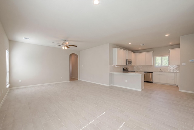 unfurnished living room with ceiling fan and sink