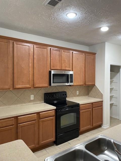 kitchen featuring a textured ceiling, sink, backsplash, and black range with electric cooktop