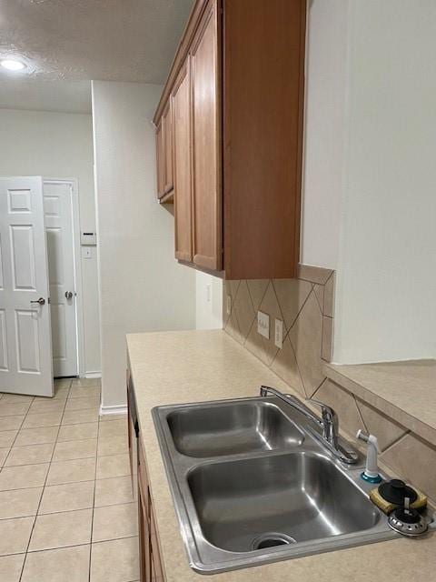 kitchen featuring decorative backsplash, light tile patterned floors, and sink