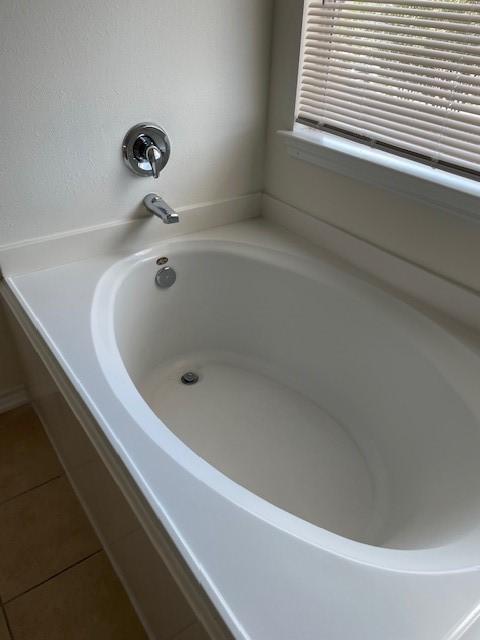 bathroom featuring a relaxing tiled tub and tile patterned floors