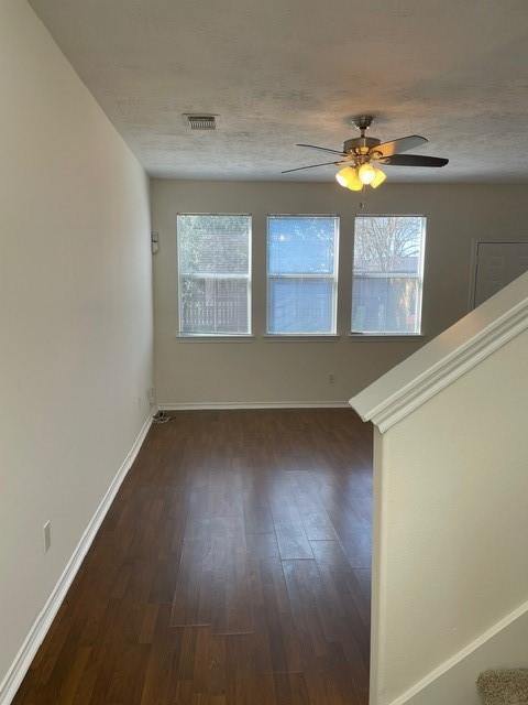 spare room featuring dark wood-type flooring, ceiling fan, and a textured ceiling