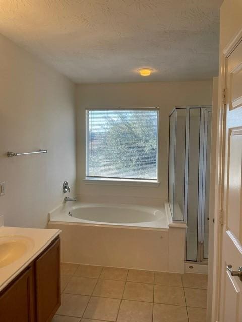 bathroom with tile patterned flooring, vanity, a textured ceiling, and separate shower and tub