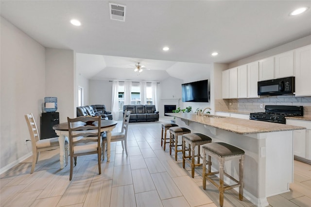 kitchen featuring white cabinets, sink, a center island with sink, and black appliances