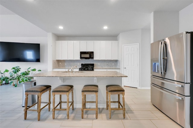 kitchen featuring white cabinets, sink, an island with sink, and black appliances