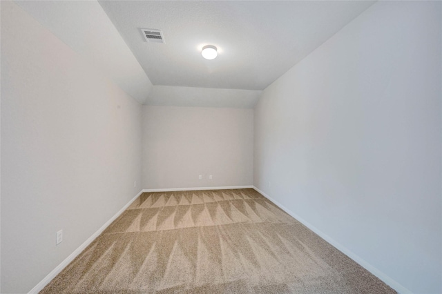 carpeted empty room with vaulted ceiling