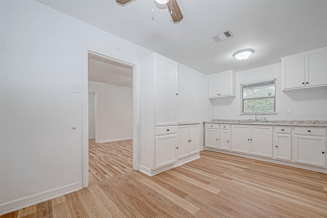 kitchen featuring white cabinets, light wood-type flooring, and sink