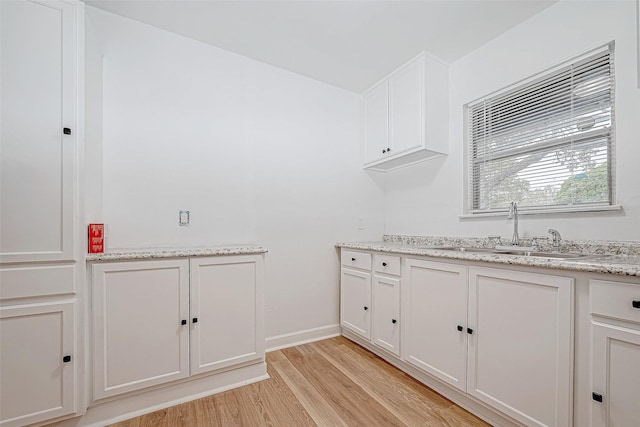 clothes washing area featuring sink and light wood-type flooring