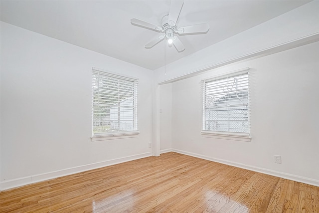 empty room featuring a wealth of natural light, ceiling fan, and light wood-type flooring