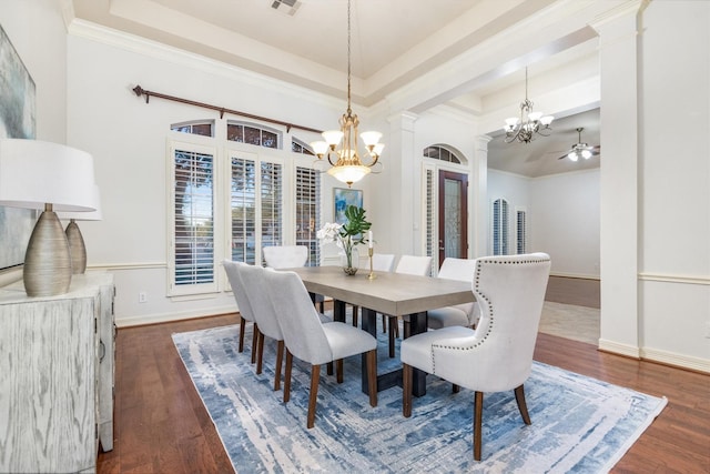 dining space featuring dark hardwood / wood-style flooring, ceiling fan with notable chandelier, a raised ceiling, and ornamental molding