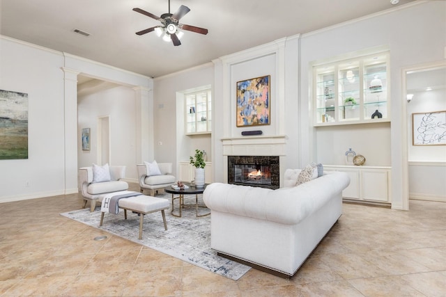 living room featuring ceiling fan, light tile patterned flooring, crown molding, and a tile fireplace