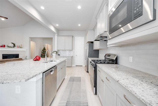 kitchen with decorative backsplash, appliances with stainless steel finishes, light stone countertops, sink, and white cabinets