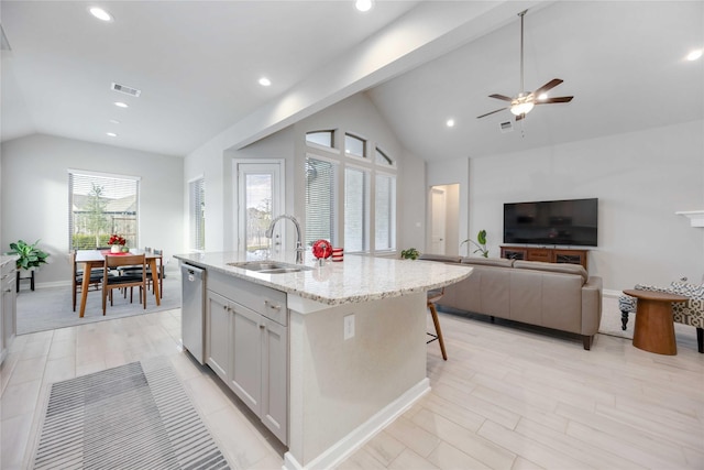 kitchen with light stone countertops, sink, dishwasher, white cabinetry, and an island with sink