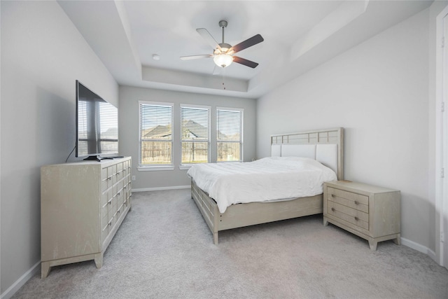 carpeted bedroom with a raised ceiling and ceiling fan