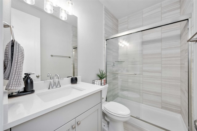 bathroom featuring vanity, a shower with shower door, and toilet