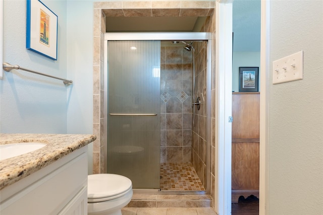 bathroom featuring tile patterned floors, vanity, toilet, and a shower with door