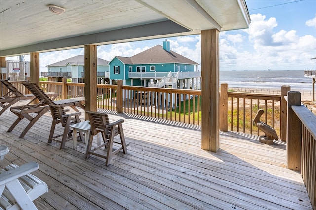 wooden terrace featuring a view of the beach and a water view