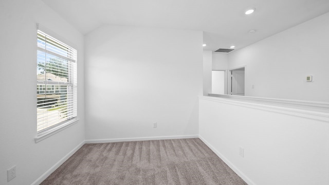 spare room with light carpet, plenty of natural light, and lofted ceiling