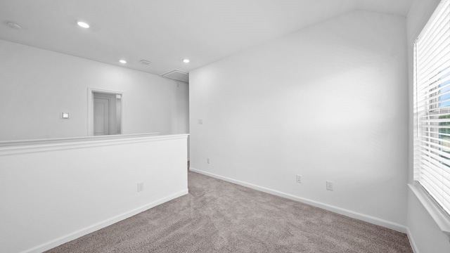 unfurnished room with light colored carpet and vaulted ceiling