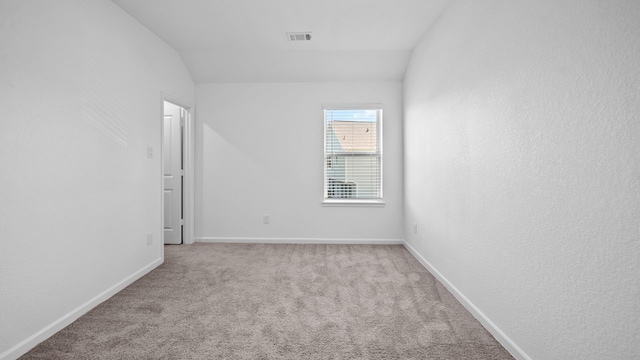 carpeted empty room featuring vaulted ceiling