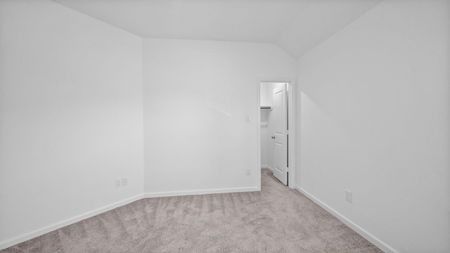 carpeted spare room with vaulted ceiling