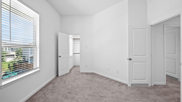 unfurnished bedroom with light colored carpet and a closet