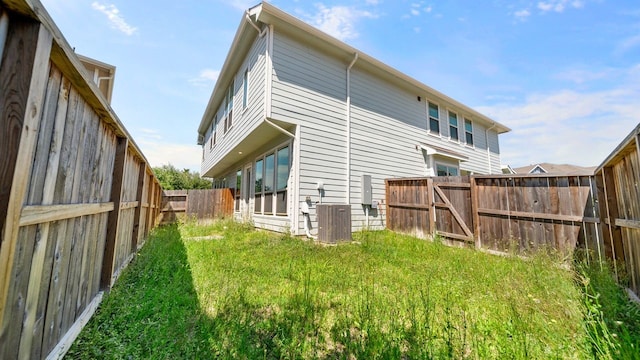 back of house with a yard and central AC